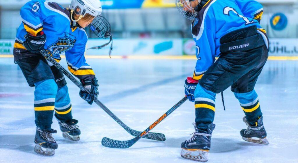 Zwei Eishockey-Spieler stehen sich gegenüber und bereiten sich auf den Puck-Einwurf vor, beide tragen hochwertige Eishockey-Schlittschuhe. Schlittschuhe kaufen für mehr Stabilität und Geschwindigkeit im Spiel.